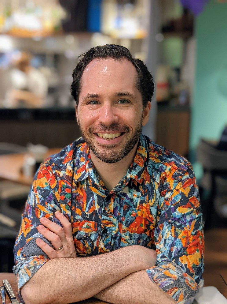 Picture of Jeff Moore, smiling, arms crossed, in a brightly colored shirt.